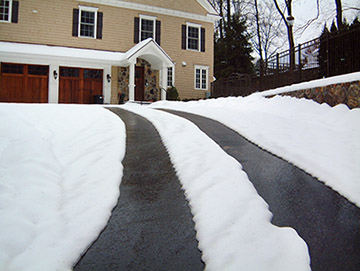 Asphalt driveway with heated tire tracks.